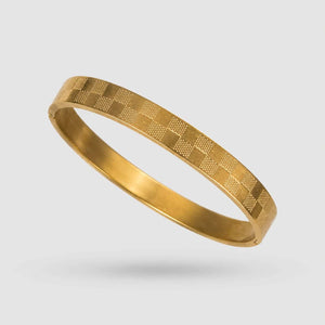 A gold bangle bracelet with a textured checkerboard pattern, shown floating against a light gray background.