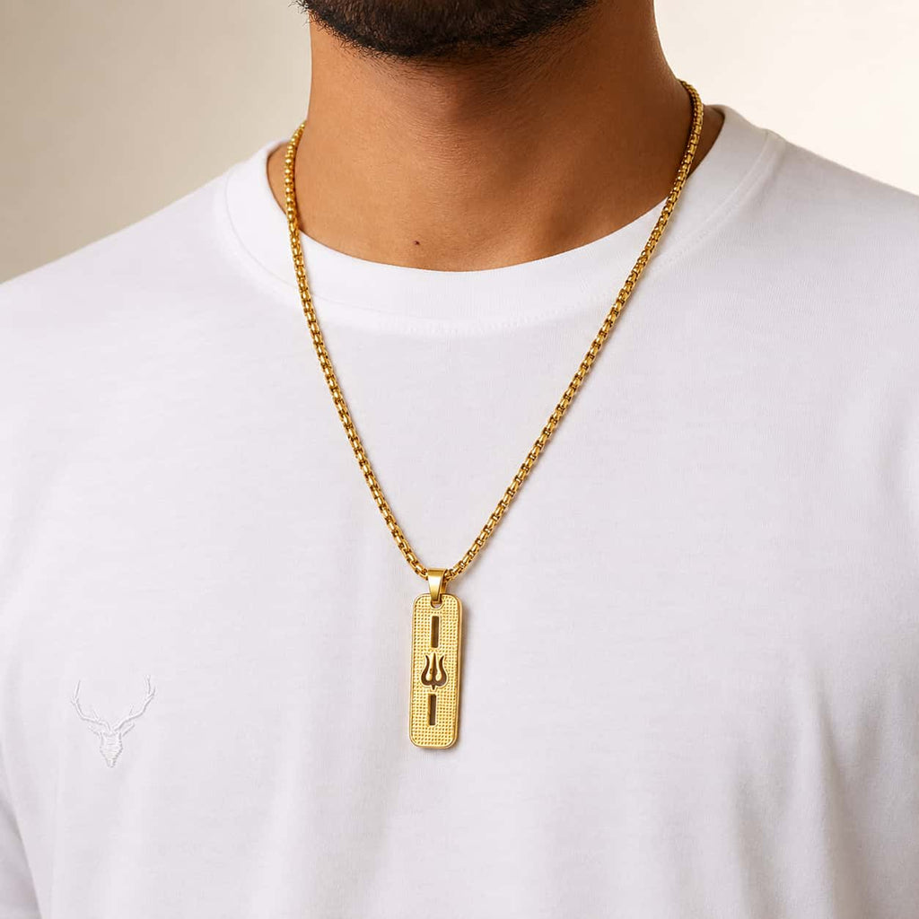 A gold-plated rectangular pendant necklace with a trident symbol, worn on a model's neck over a white t-shirt.
