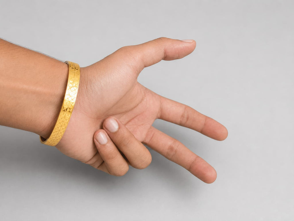 A gold textured bangle bracelet worn on a person's wrist, shown against a plain light gray background.