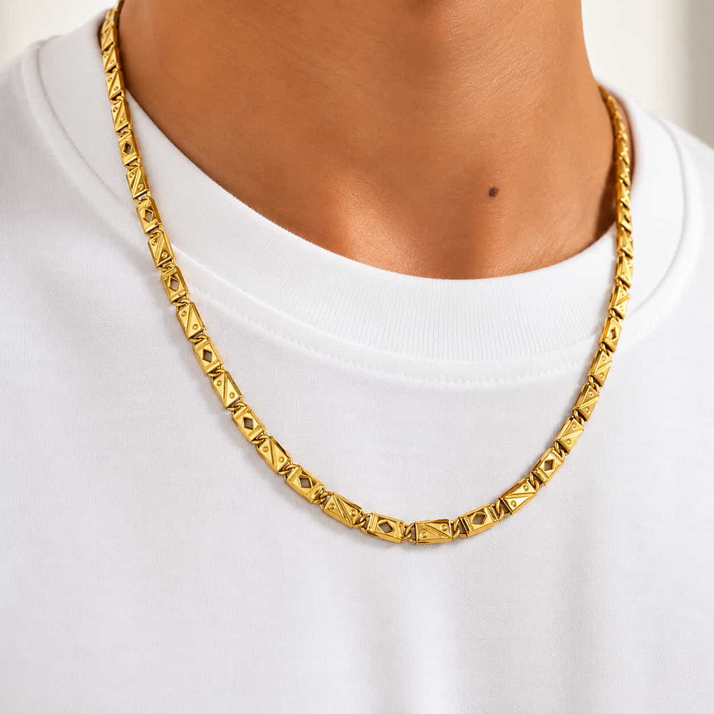 A close-up of a person wearing a textured gold chain necklace over a white crewneck t-shirt.