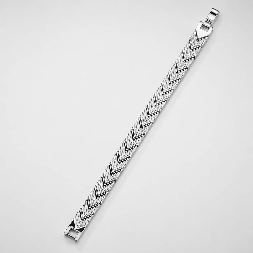 A silver-toned metal bracelet with a textured chevron or herringbone pattern, shown diagonally on a plain light gray background.