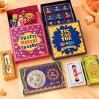 A collection of colorful Indian-themed gift boxes and cards arranged on a peach fabric background. Visible items include a pink 'Khatti Meethi Yaadein' box, a blue 'Tic Tac Toe Sis & Bro' box, a small 'Fatafi' box, a 'Joker' playing card, and other decorative gift packaging.