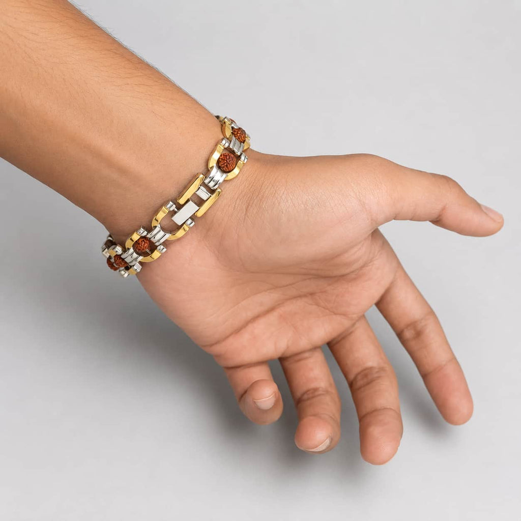 A two-tone gold and silver chain bracelet with round brown beads, shown worn on a person's wrist against a plain light gray background.