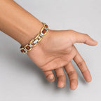 A two-tone gold and silver chain bracelet with round brown beads, shown worn on a person's wrist against a plain light gray background.