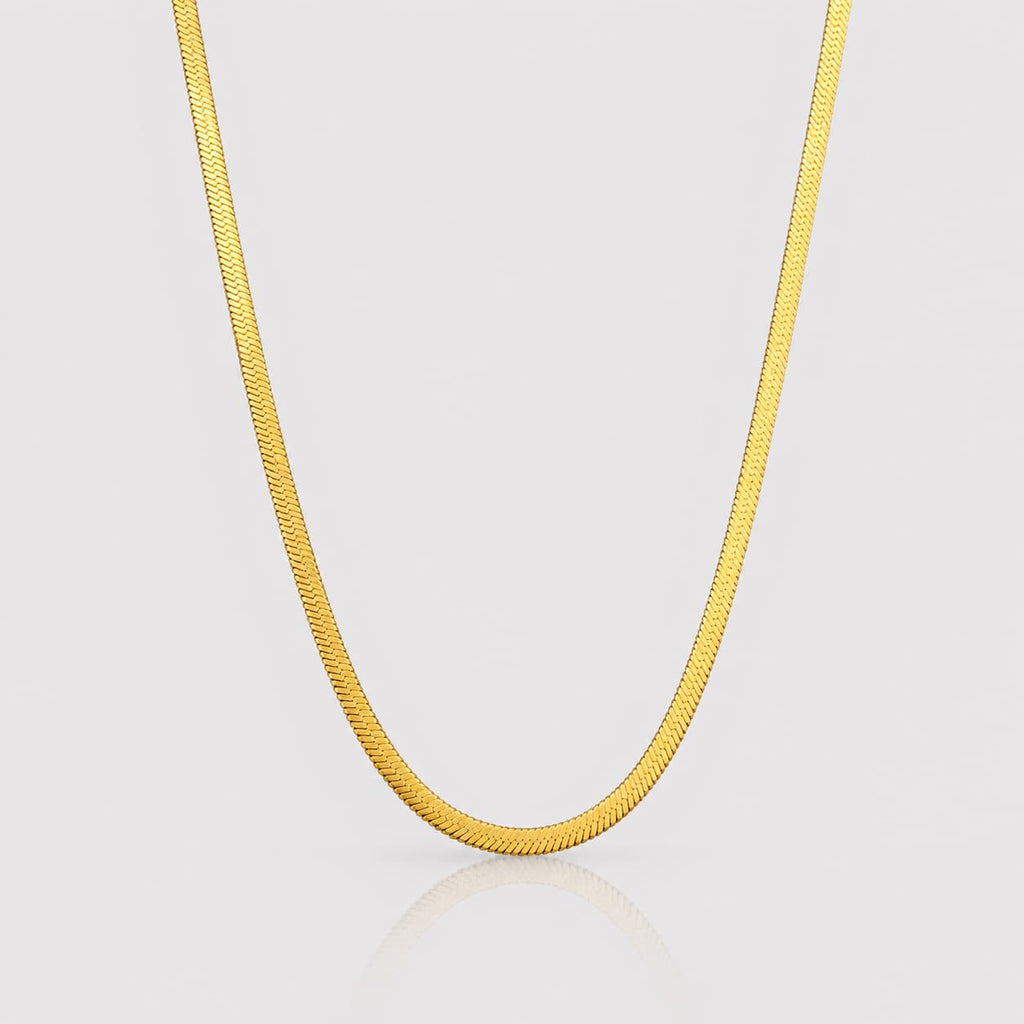 Gold chain necklace on a light gray background
